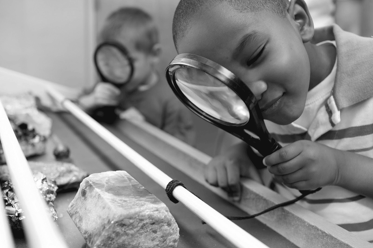 Young boy inspecting minerals with magnifying glass